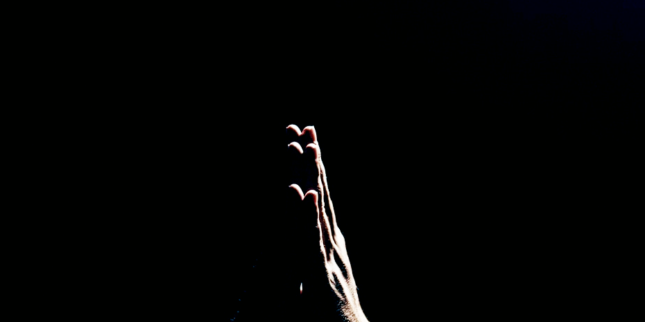 hand praying against black backdrop